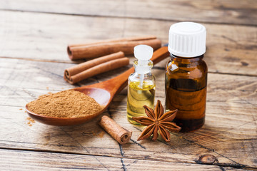 Essential aroma oil with cinnamon and star anise on wooden background. Selective focus.