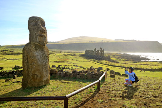 Female tourist taking photo of the solitary "Traveling Moai" at the entrance to Ahu Tongariki of famous 15 Moais, Easter Island, Chile