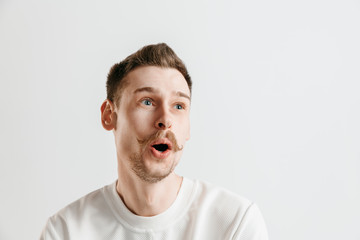Wow. Attractive male half-length front portrait on gray studio backgroud. Young emotional surprised bearded man standing with open mouth. Human emotions, facial expression concept