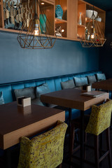 Retro bar iron lamps, chartreuse velvet chairs and deep blue accent walls. Modern cafe interior design concept. Nautical minimalist style. 