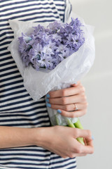 A Girl In A Striped T-shirt Holding Little Bouquet Of Spring Flowers Hyacinths Wrapped In White Paper