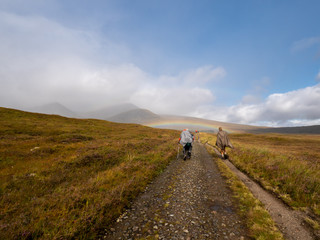 Fototapeta na wymiar a man and a woman hiking with rainbow through bog