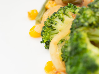 cooked vegetables broccoli, carrots, green beans, corn on a white plate. macro