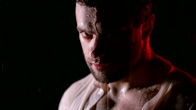 Close-up of a angry guy in the rain in white unbuttoner shirt, rage in eyes.