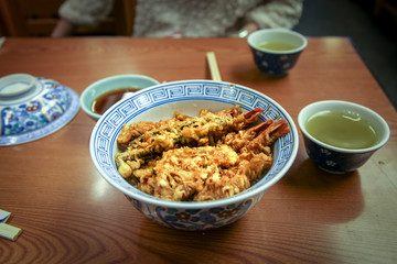Tempura Donburi or ten don japanese shrimp and vegetables tempura on rice with sauce on the table .