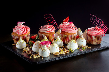 Cupcakes with pink cream, meringues sprinkled with nuts.