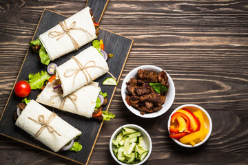 Burritos tortilla wraps with beef and vegetables top view.