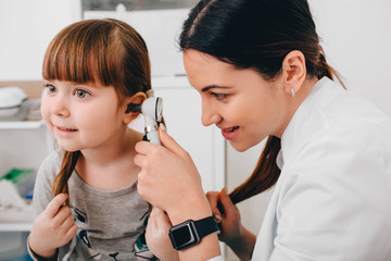 audiologist examining little patient with otoscope, hearing exam of child