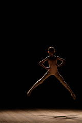 Young excited girl jumping in the studio or on the stage.