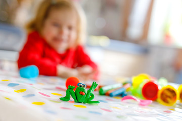 Adorable cute little toddler girl with colorful clay. Healthy baby playing and creating toys from...