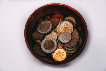 a bowl filled with various coins from different countries stands on a white surface