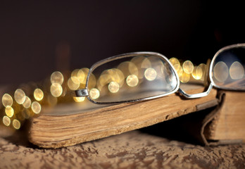 Old glasses lying on a vintage book with a blurred background and beautiful bokeh