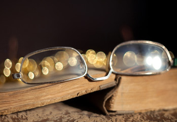 Old glasses lying on a vintage book with a blurred background and beautiful bokeh