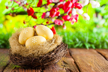 Three painted Easter eggs in the nest on table and nature background