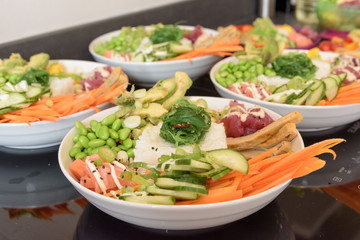 Large poke bowls lined up to be served, with deliciously fresh food
