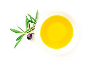 A photo of an olive tree branch with a berry and green leaves, shot from the top on a white background with olive oil and copy space