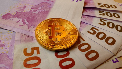 Bitcoins, an virtual currency in physical coin form, displayed on 500 Euro banknotes