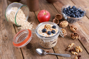 Obraz na płótnie Canvas Healthy breakfast with yogurt on oatmeal muesli and walnuts, in a glas on a rustic wooden table.