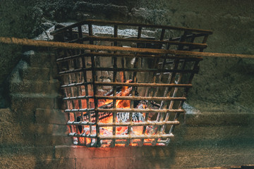 Fire wood inside an iron cage hanging on a bricks wall