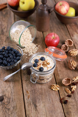 Obraz na płótnie Canvas light healthy breakfast with yogurt on oatmeal muesli , blueberries and walnuts in a glas on a rustic wooden table