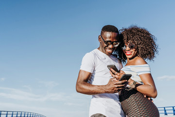 Two happy friends using the mobile in the street. Friendship concept.