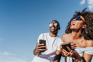 Two happy friends using the mobile in the street. Friendship concept.