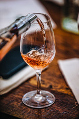 A glass of rose wine at a table tasting.
