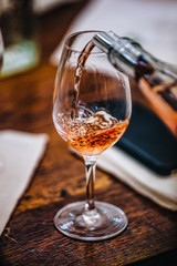 A glass of rose wine at a table tasting.