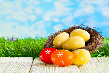 Painted Easter eggs in the nest and wooden table