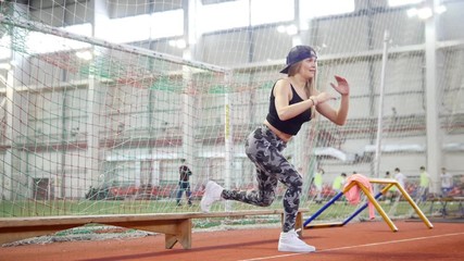 Young athletic woman in leggins doing nice leg exercises using a bench