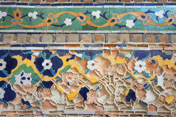 Fragments of ancient eastern mosaic that needs restoration on the walls of Khiva fortress in Uzbekistan