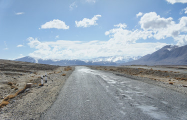 An empty road in snowy Pamir mountains on the background between Tajikistan and Kirgyztan border. Inspirational landscape. 