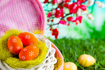 Easter eggs in the nest and pink basket on nature background