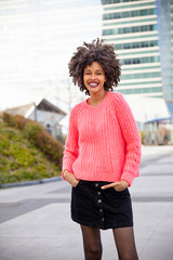 Beautiful young girl with curly brown hair with pink sweater in town © Sergio