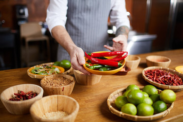 Mid section portrait of professional chef holding chili peppers and spices while cooking in restaurant kitchen, copy space