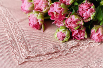 Pink plaid on the edges decorated lace. Bouquet of terry pink tulips is on top. The focus is on the plaid.