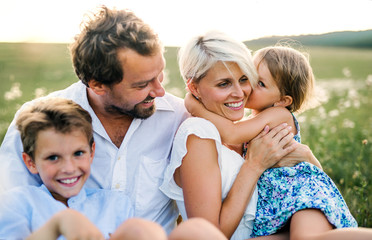 Young family with small children in summer nature at sunset.