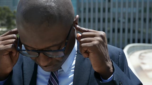 Businessman puts in Apple earbuds and is happy when he hears music.