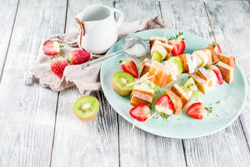 Summer breakfast snack. Fruit vegan dessert kebabs on skewers with toast French fried bread, fruits and berries. With powdered sugar and chocolate sauce.