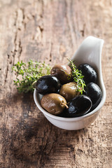 Bowl filled with freshly harvested whole fresh olives and oil on a rustic wooden tabletop