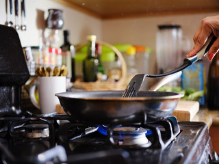 stirring strips of beef in hot skillet inside home kitchen on gas stove