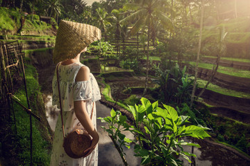 A girl in a white dress on the rice terraces of Tegallalang. Bali trip. Tropical landscape. Travel.	