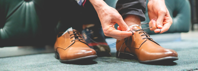 elegant businessman try on new brown classic shoes