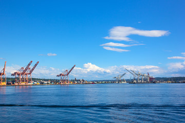 Port panorama on a sunny afternoon in Seattle, USA. Cranes, vessels and cargo containers of the city port.