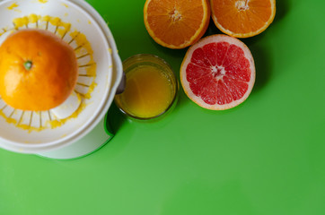Breakfast time. Squeezing orange and grapefruit on green background