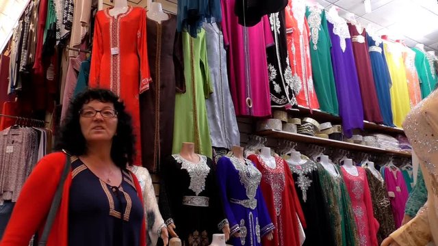 European woman tourist looking at Muslim style dresses in the Morocco market 