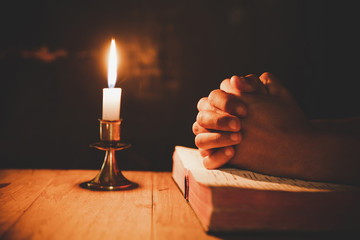 man praying on the Bible in the light candles selective focus