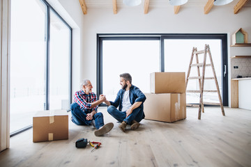 A mature man with his senior father furnishing new house, a new home concept.