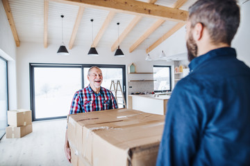 A senior man helping his son with furnishing new house, a new home concept.