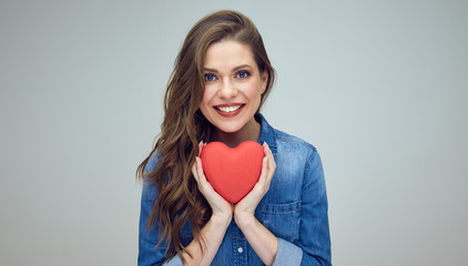 woman with toothy smile holding red heart.